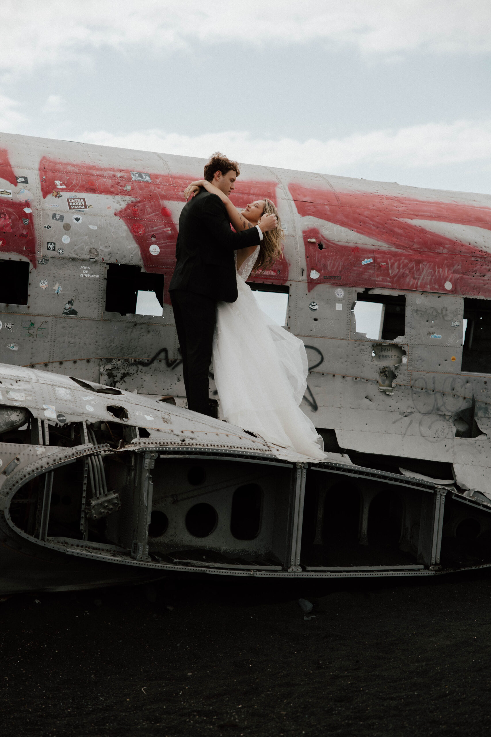Iceland elopement photographer capturing couple on plane wreck at black sand beach in Iceland